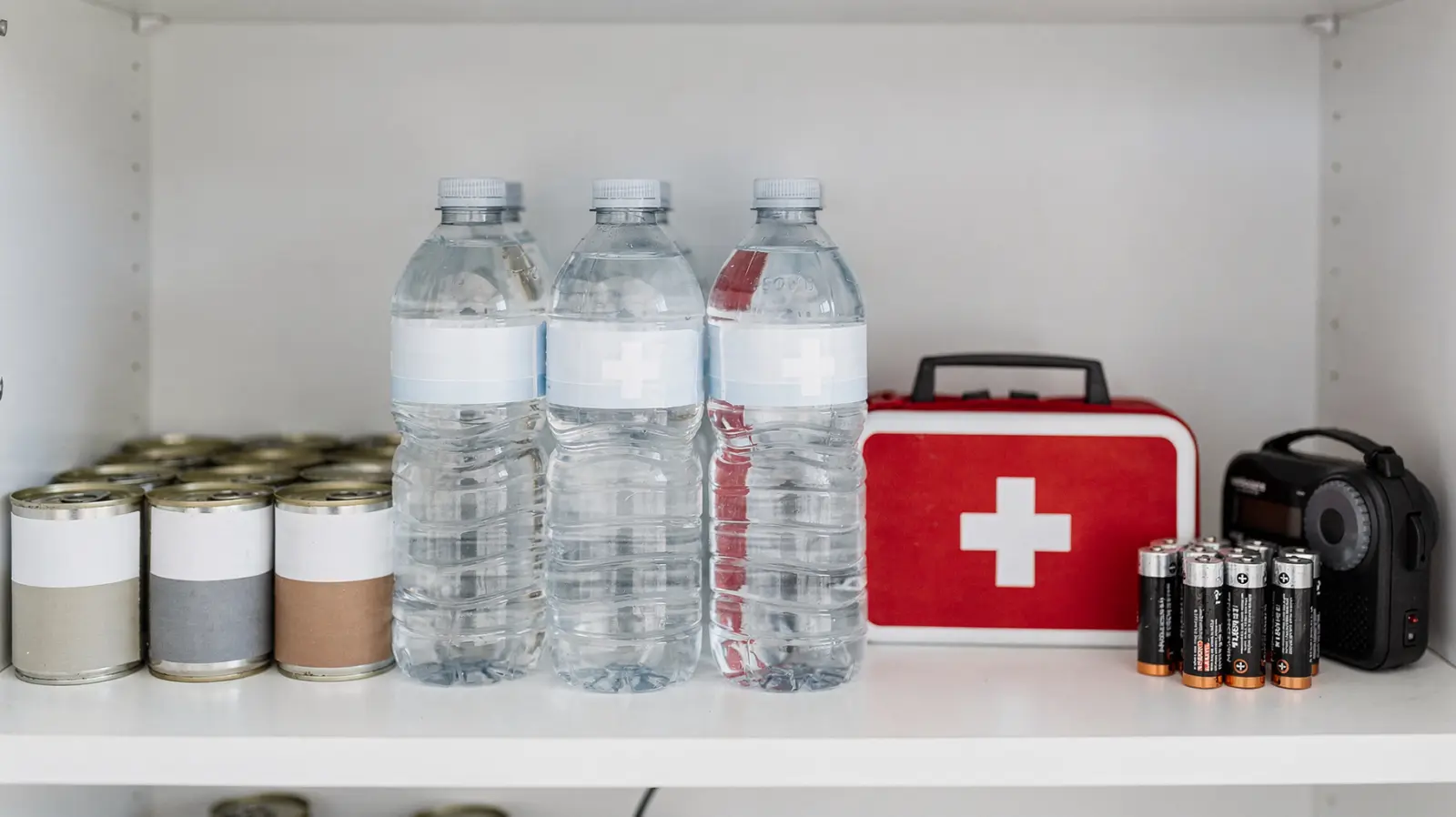 Notvorrat mit Wasser, Konserven und Taschenlampe in einer aufgeräumten Speisekammer